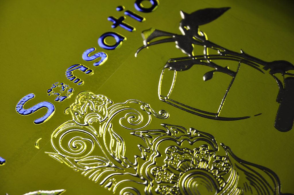 Metallic embossed illustration on green stock featuring raised floral detailing and glossy sculpted varnish effects