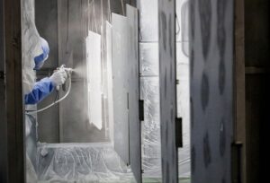 A Horizon Finishing factory worker is seen painting exterior machine covers in a clean paint area.